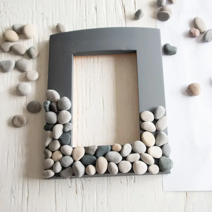Half of the painted picture frame covered with rocks.