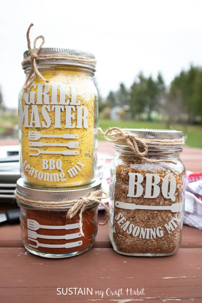 Three mason jars filled with BBQ seasoning and labelled with phrases such as "grill master" and " BBQ Seasoning mix." as a Father's Day BBQ gift idea