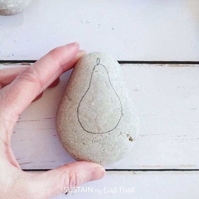 Outlining a pear shape on a rock.