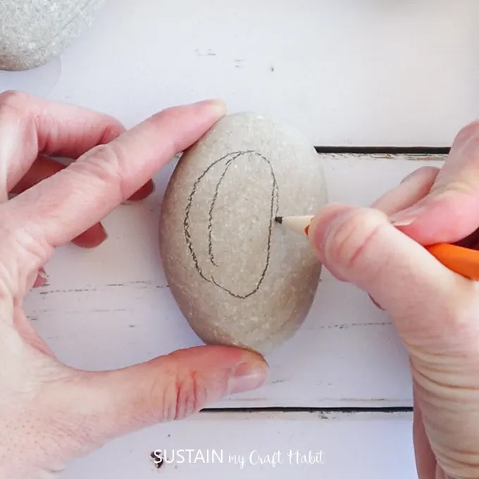 Using a pencil to sketch a plum shape on a rock.