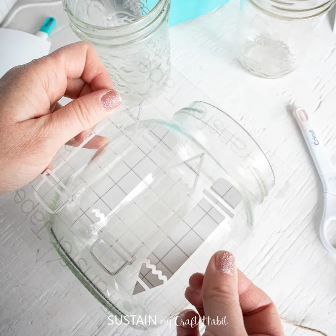 placing the Smart Vinyl cut image onto a large mason jar for holding pens