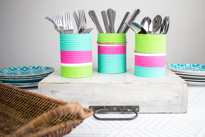 Finished colorful utensil holders with forks, knives and spoons placed a white serving tray.
