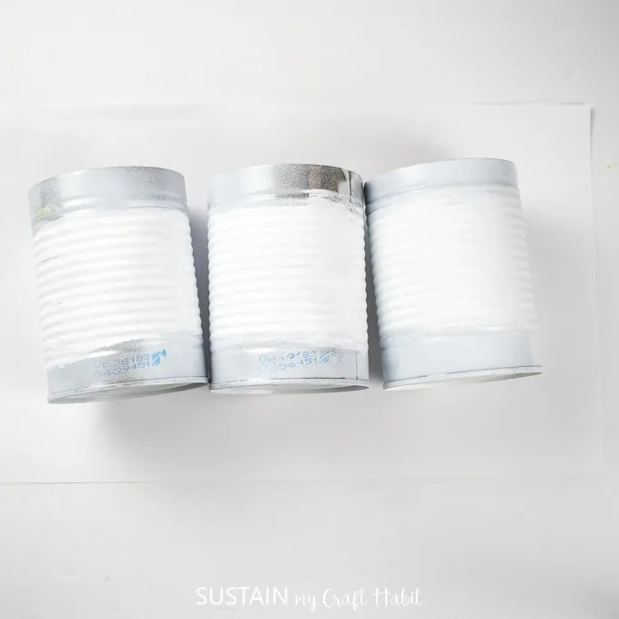 Three white painted tin cans.