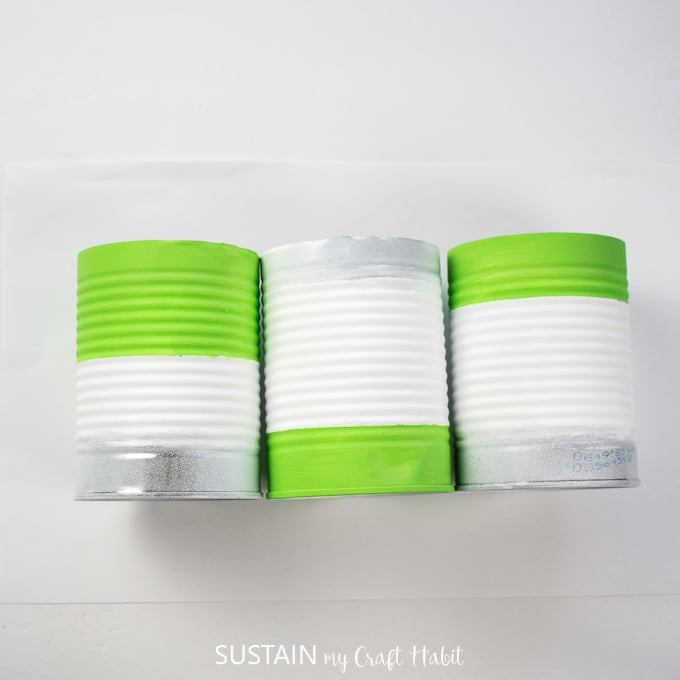 Showing three tin cans painted green and white.