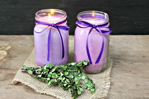 Two purple mason jar lavender candles lit up.