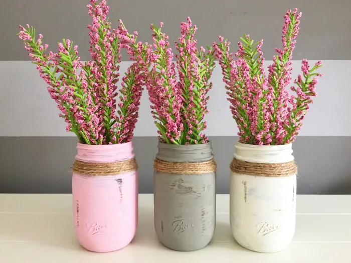 Mason jar crafts painted into pink, great and white flower centerpieces.