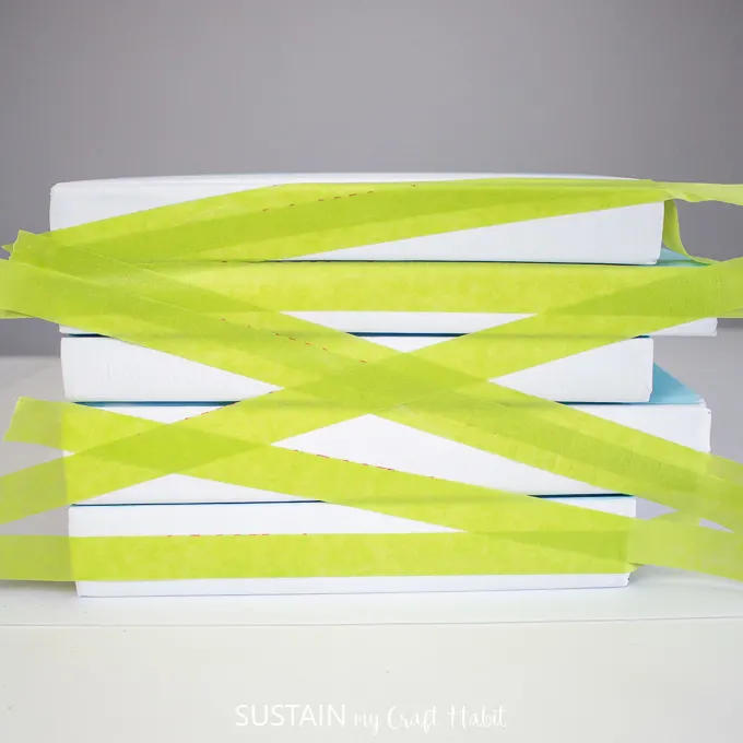 Covering the stacked books with green painters tape 