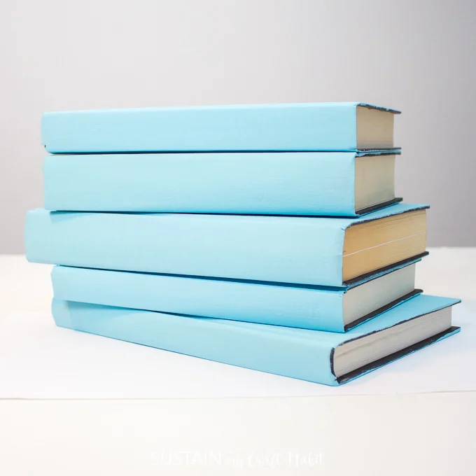 Stacking the blue painted hardcover books horizontally.