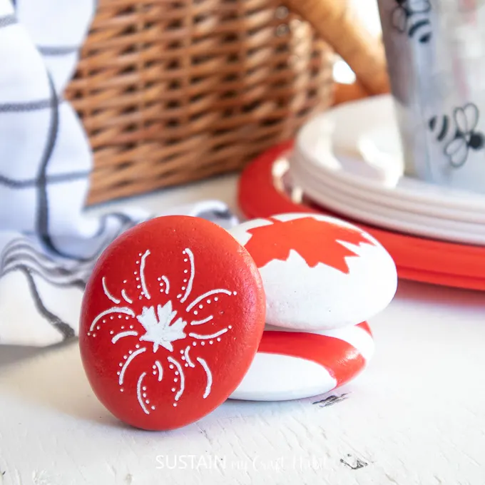 3 painted rocks in red and white colors and Canadiana inspired.