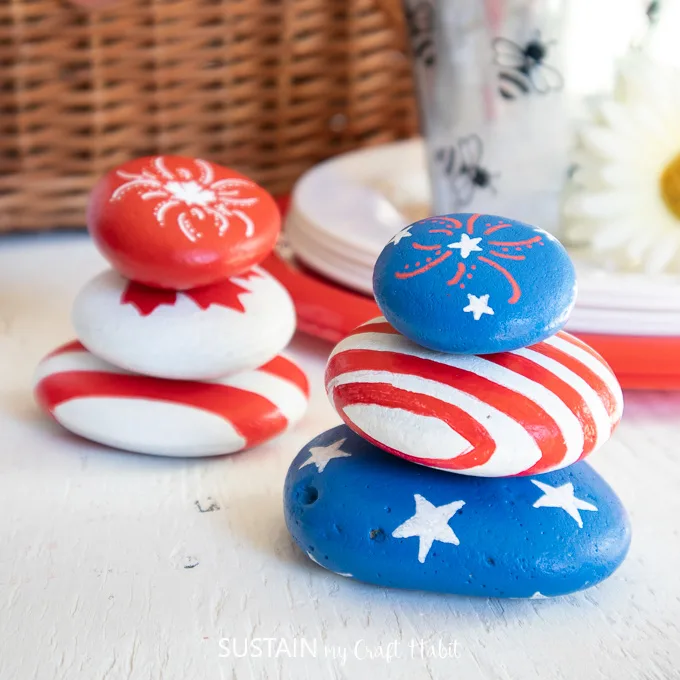 American and Canadian inspired painted rocks styled in front of a picnic basket and dishes.