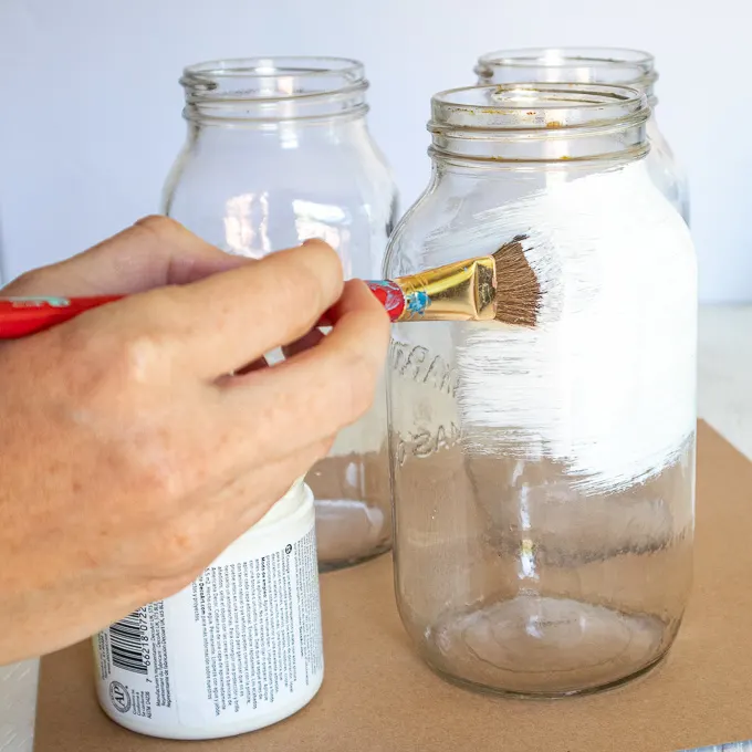 Painting the mason jar with white paint.