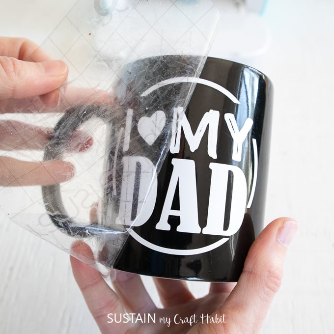 Removing the transfer tape and leaving the "I heart my dad" vinyl image on the black mug.