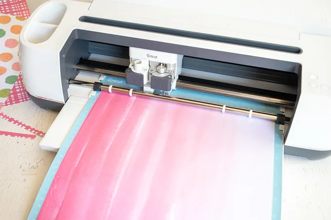 Loading pink paper into the Cricut machine.