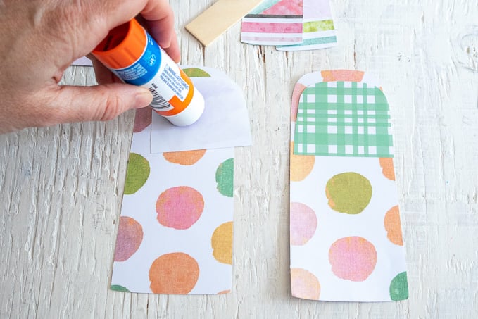 Gluing smaller pieces of paper onto the popsicle cut out.