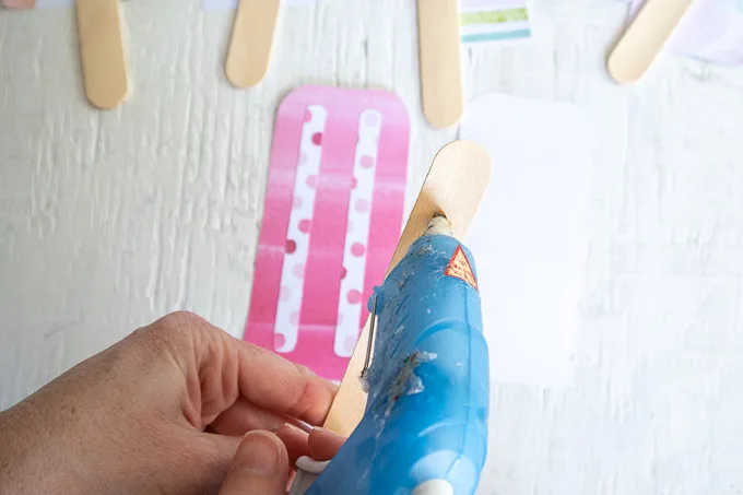 Adding hot glue to a popsicle stick.
