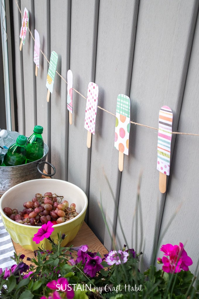 Colorful paper popsicle garland decor hung against a grey wall.