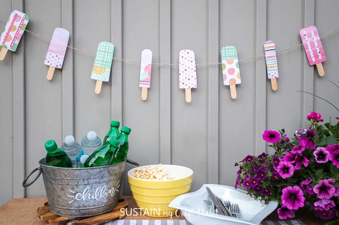 Colorful paper popsicle garland decor hung against a grey wall.