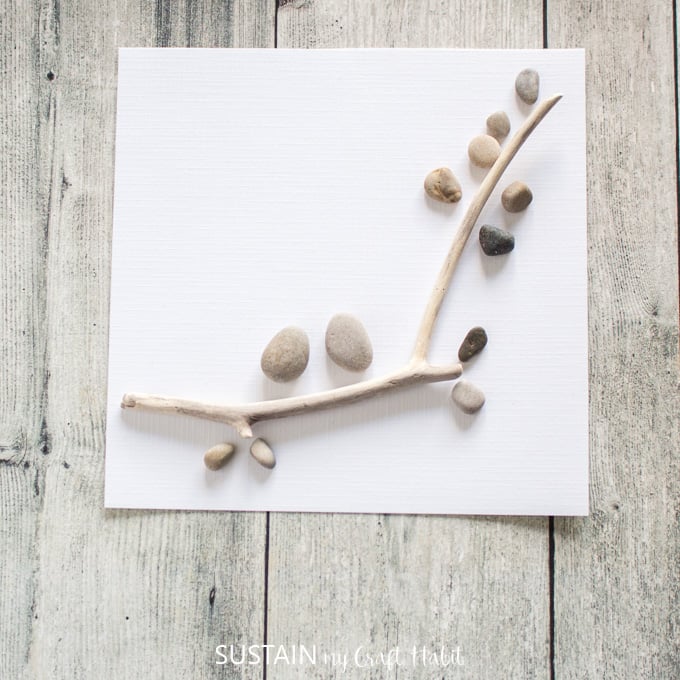 Adding smaller sized pebbles along the edges of the twig.