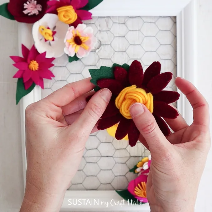 Preparing to glue a felt flower into the picture frame.