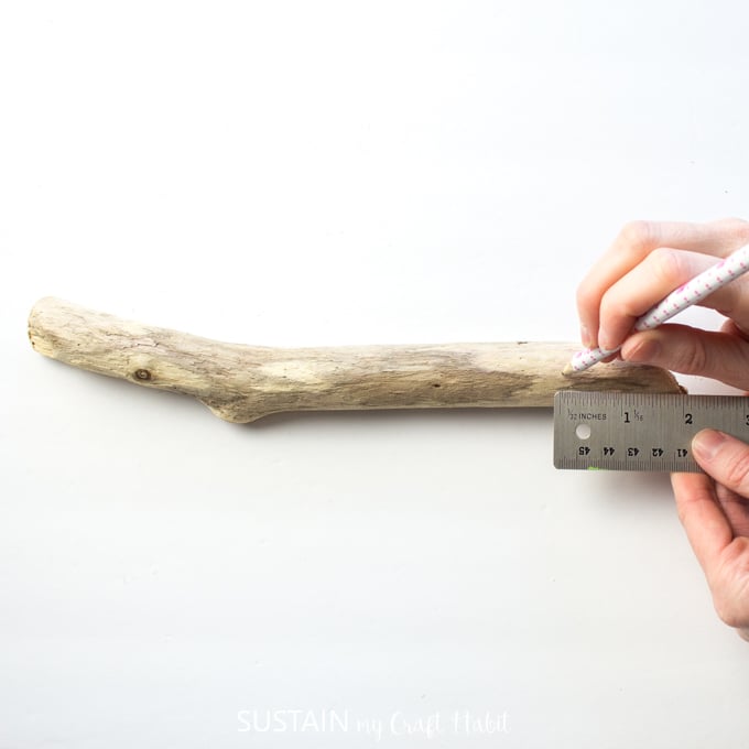 Using a pencil to measure 2 inches from the side of the driftwood piece.