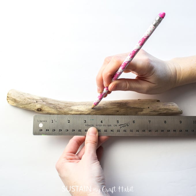 Adding evenly spaced pencil marks on a driftwood piece.