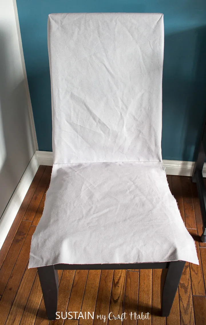 Placing the in-process dining chair slipcover over the chair in order to check the sizing.