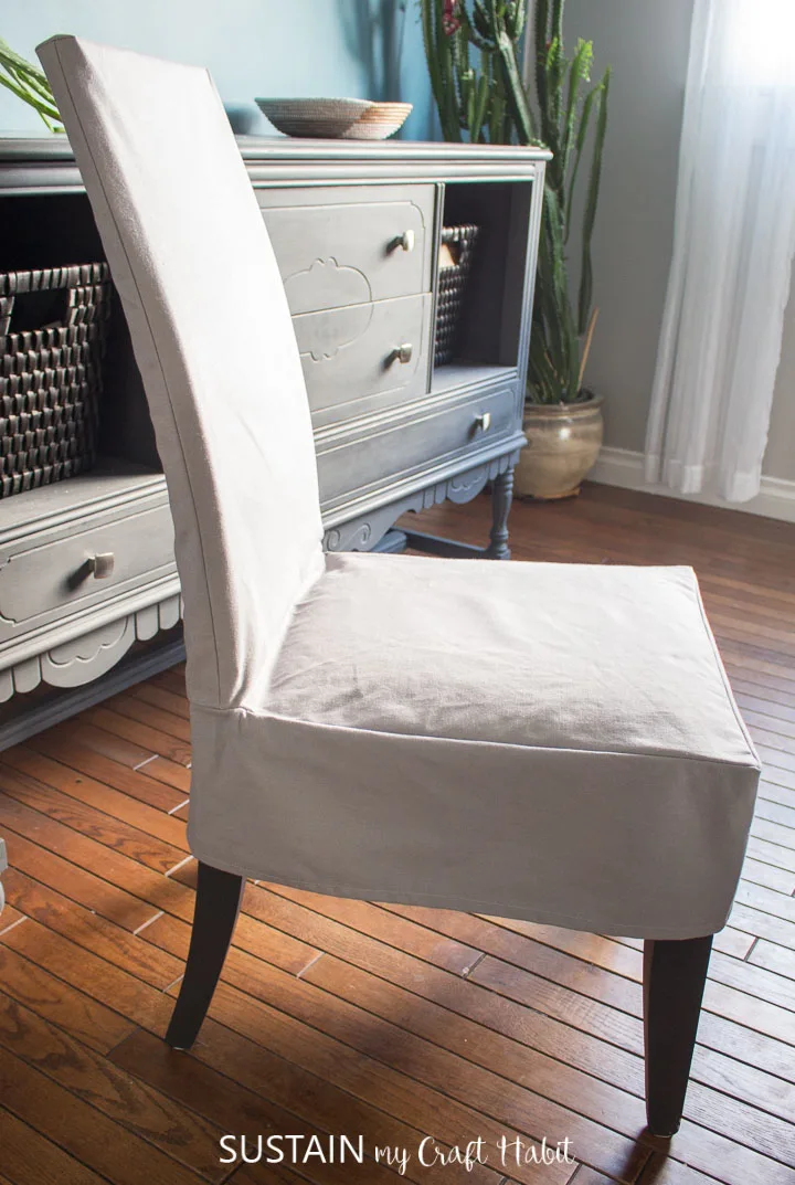 Side view of a completed dining room chair slipcover made from light grey cotton canvas.