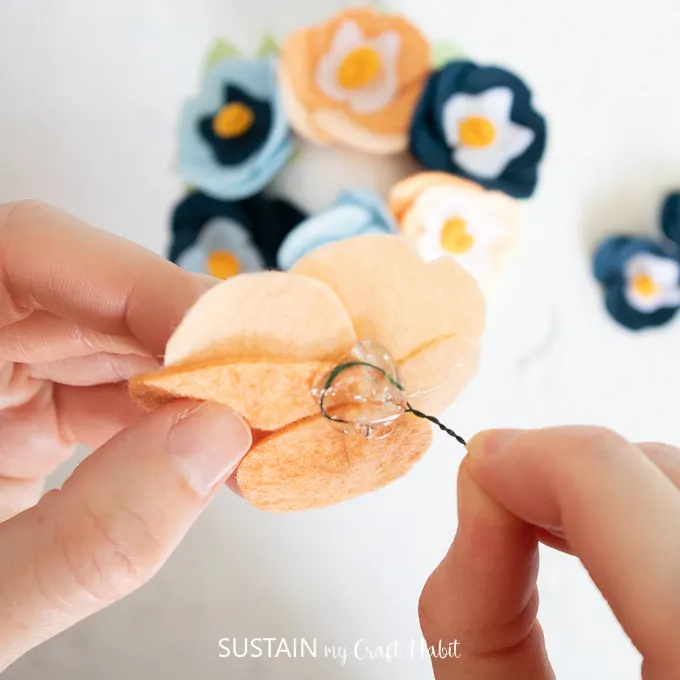 Gluing floral wire to the back of a felt pansy flower.