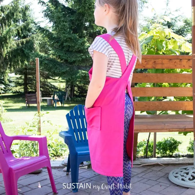 Side view of a child wearing the pink apron.