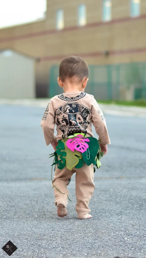 Back view of a toddler wearing a onesie made to look like Disney's Maui character.