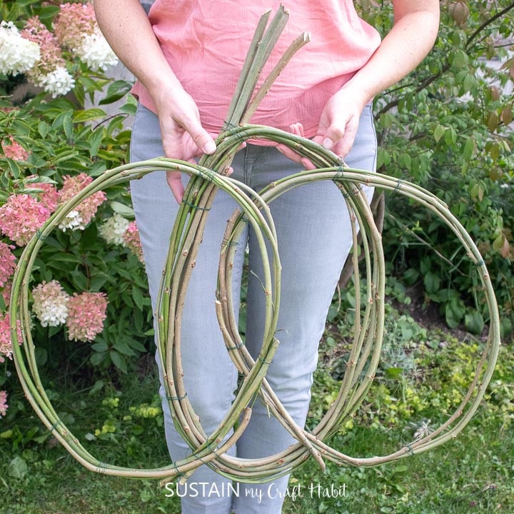 holding a large pumpkin wreath form made from vines