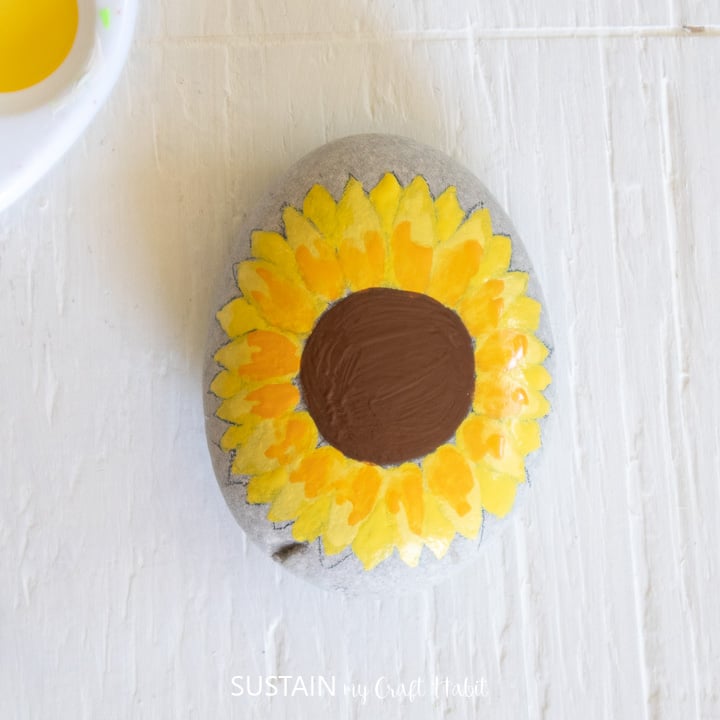 Painting a brown circle in the center of the yellow petals.