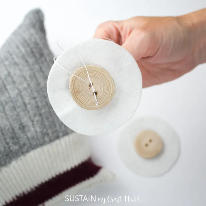 Sewing buttons onto the middle of the felt circles.