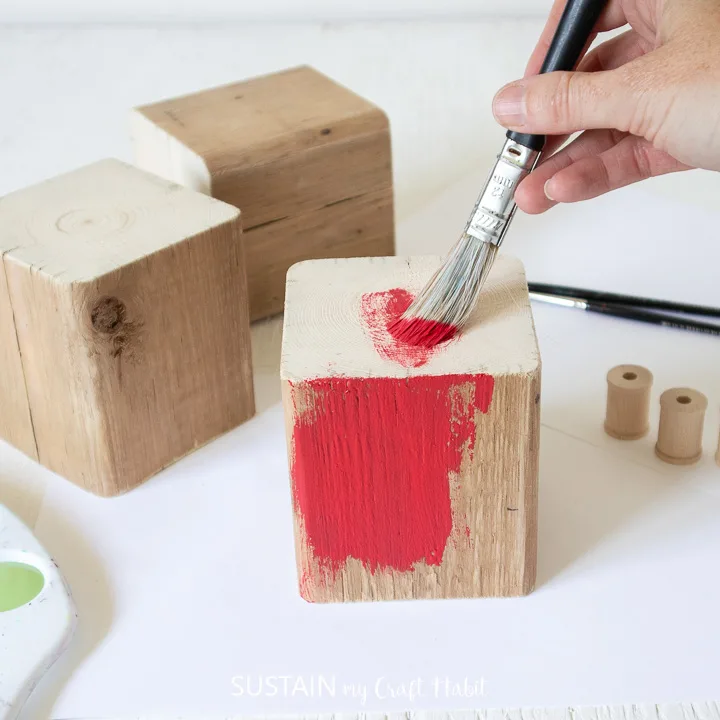 Painting a wood block red.