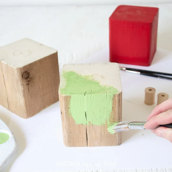 Painting a wood block green.