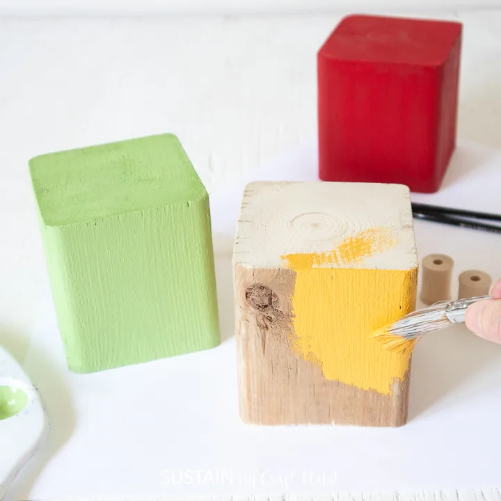 Painting a wood block yellow.