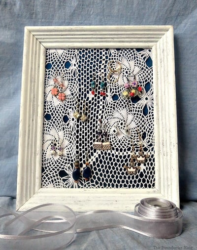 A wood photo frame with a crochet doily to organize and display earrings.