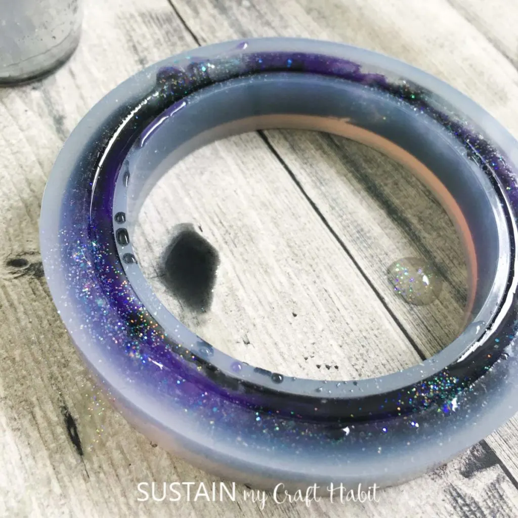 The bracelet mold filled to the top with resin and glitter.