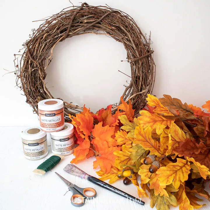 Gathering the supplies needed to make a DIY metallic fall leaf wreath.