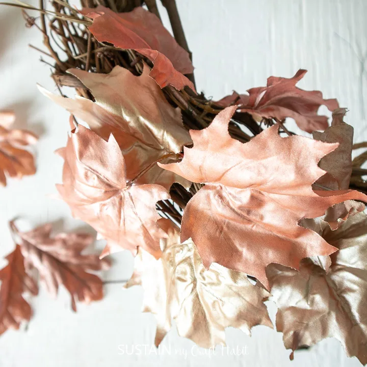 Adding painted faux maple leaves to the grapevine wreath.
