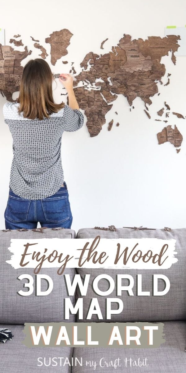 Woman installing the 3D world map on a white wall.