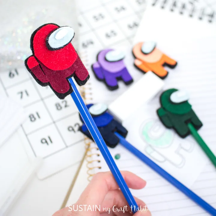 someone writing with a pencil with anAmong Us pencil topper on the end