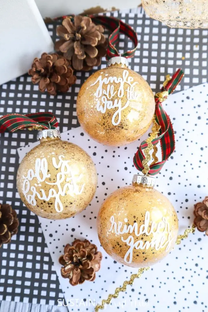 Glittering gold painted glass ornaments. with vinyl sayings on the front.