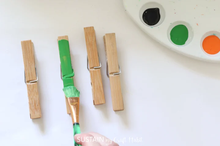 Painting one of the four clothespins green.