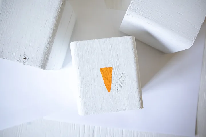 Painting an orange triangle on the wood block.