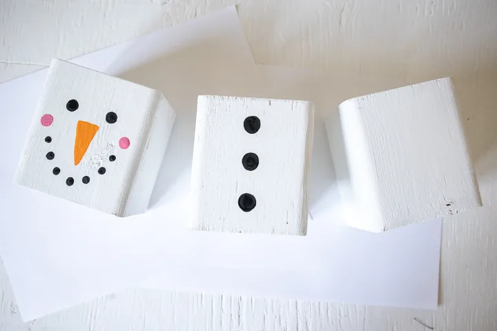 Painting black circles on another wood block to resemble snowman buttons.