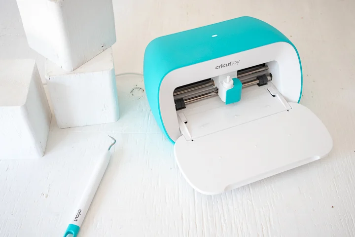 Cricut Joy machine alongside painted wood blocks and a weeding tool.