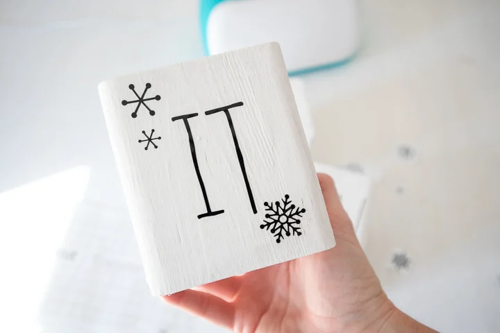 Wood block with snowflake images and the word "it."