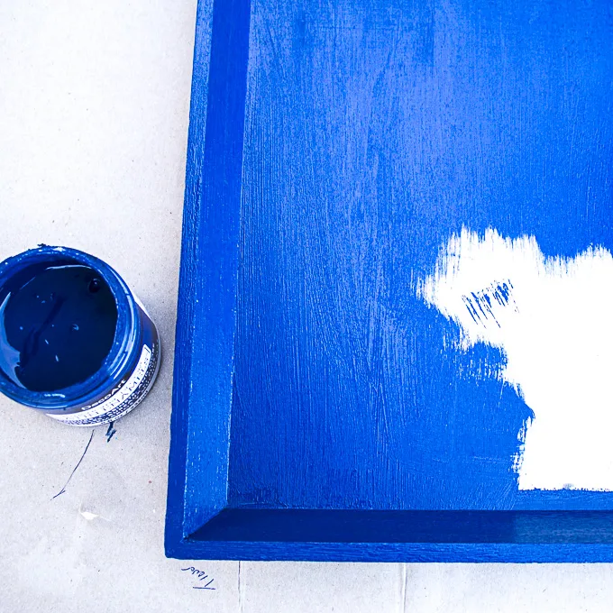 Painting a wood tray blue.
