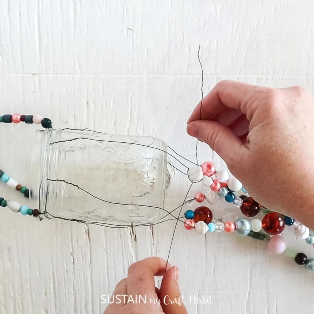 wrapping a piece of wire around the top of the beaded strands just under the mason jar. 